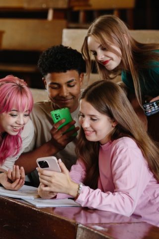 A group of students smiling while using VisionXI on their smartphones in a classroom.